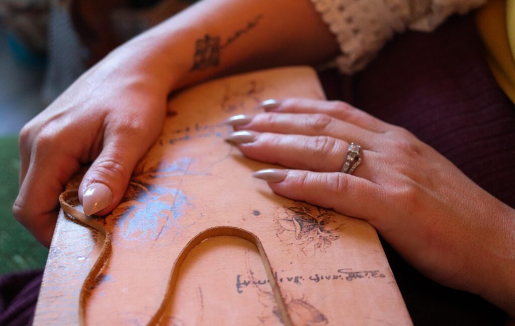 Closeup of hands with long beige painted nails covering an ancient spiritual book